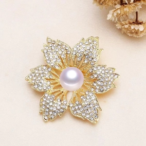 Elegant gold flower brooch with sparkling rhinestones and a central pearl on textured fabric