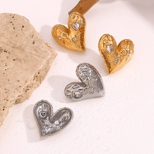 Macro view of gold and silver heart earrings with hammered texture and inset diamonds