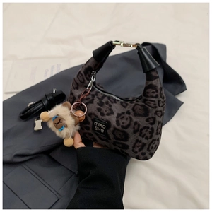 Detail of dark grey leopard print handbag featuring a cute plush animal charm and handle