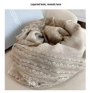 Detail of light brown linen scarf featuring layered white lace trim and soft knit texture