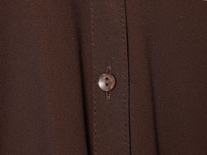 Close-up of a dark brown pleated midi dress showing shell texture button and fabric detail
