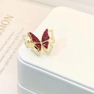 Macro shot of gold butterfly brooch with red gemstones and clear crystals on a jewelry box