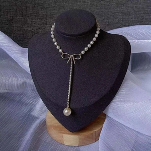 Detail of elegant bowknot pendant with white pearls and gold tassel on a display