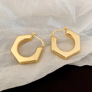 Detailed view of chunky golden hexagonal geometric hoop earrings with a secure hinged closure