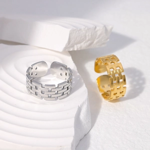 Close-up of gold and silver open rings with brick chain hollow texture on stone props