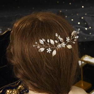 Detailed close-up of golden leaf bridal hair comb with crystal and pearl embellishments