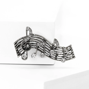 Macro shot of retro alloy music note brooch with silver finish and sparkling crystals