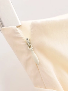 Close-up of invisible zipper and fabric texture on cream mini skirt side seam