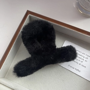 Dettaglio di un fermaglio per capelli in peluche nero morbido su un vassoio decorativo in legno