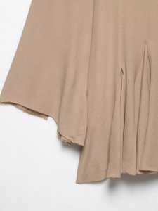 Detail of khaki chiffon dress hem featuring asymmetric cut and raw edge fringe design