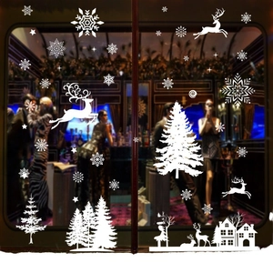 White Christmas window decals featuring reindeer, snowflakes and trees on a glass storefront