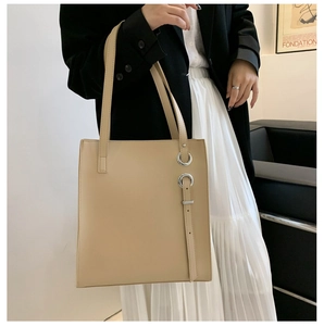 Detail of minimalist beige faux leather tote bag with metal ring buckle on modern model