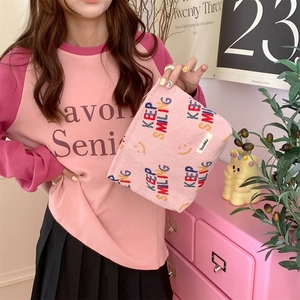 Detailed texture of pink corduroy makeup bag with KEEP SMILING print and logo
