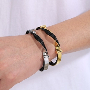 Close-up of gold and silver twisted C-shape bracelets with woven leather on male wrist