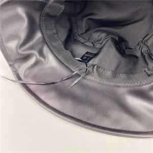 Detail of black faux leather bucket hat showing interior fabric lining and adjustable strap