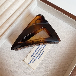 Close-up of large tortoise shell triangle hair claw clip with golden metal spring