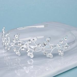 Detailed close-up of silver rhinestone tiara with elegant leaf motifs on a sleek surface