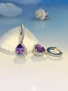 Macro shot of silver drop earrings with pear-cut purple crystal and cubic zirconia