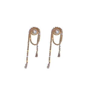 Macro view of gold tassel earrings with intricate pearls and sparkling rhinestones