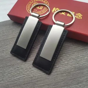 Minimalist leather and silver metal keychain set shown in 98mm length on grey wood background