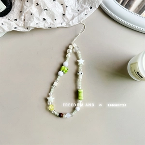 Close-up of handmade beaded phone strap featuring white pearls and green mushroom charms