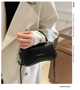 Detail of black PU leather crossbody bag featuring gold hardware and fashion text