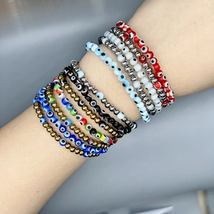 Stack of colorful evil eye beaded bracelets with 18K gold plated accents on a wrist