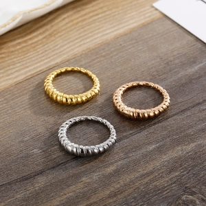 Three minimalist croissant rings in gold, silver, and rose gold finishes on wood