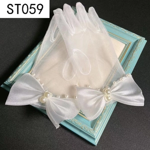 Detail of white bridal gloves featuring sheer tulle, satin bows, and elegant pearl accents