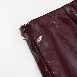 Dettaglio gonna in pelle PU bordeaux con texture pieghettata e chiusura a cerniera invisibile