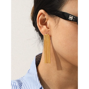Detailed close-up of golden long tassel earrings worn by a model in a side view profile