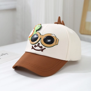 Gros plan sur une casquette enfant avec dinosaure 3D et lunettes de soleil brillantes