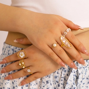 Gold stainless steel ring set with white pearls and flower motifs on a female model
