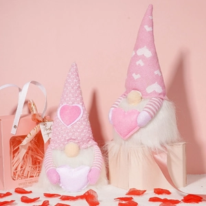 Close-up of two pink Valentine gnomes with knit hats and heart motifs on pink background