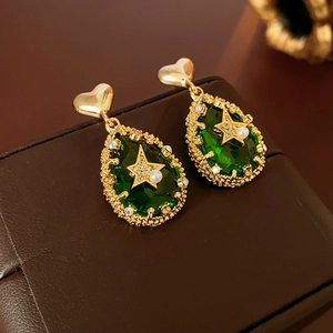 Macro shot of green teardrop earring with gold heart stud and pearl star detail