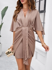 Detail of elegant champagne satin dress featuring pleated waist and batwing sleeves