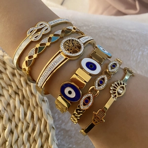 Detailed close-up of layered gold evil eye bracelets with rhinestones on model wrist