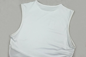 Détail d'une robe moulante sans manches blanche avec fronces latérales et tissu en mesh