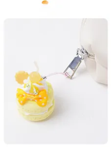 Close-up of yellow macaron dessert keychain with polka dot bow on white zipper bag