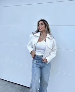 Detail of white cropped wool jacket with lapels and light blue high waist wide-leg jeans
