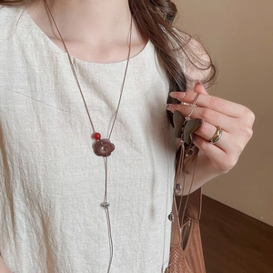 Vue détaillée du pendentif lotus en bois ethnique avec perles rouges et papillon