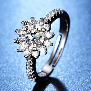 Close-up of a silver sunflower ring with a round moissanite on a starry blue background