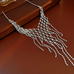 Detailed view of silver tassel necklace with rhinestones on a wooden tray display