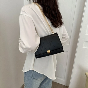 Classic black quilted crossbody bag with gold chain strap worn by a model on white background
