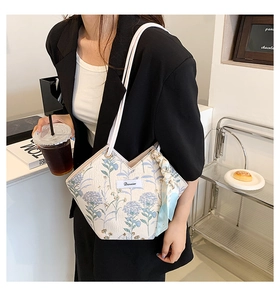 Detail of floral canvas tote bag with V-shaped opening and decorative silk scarf accessory