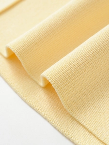 Close-up of high-quality light yellow knitted fabric with soft ribbed texture details