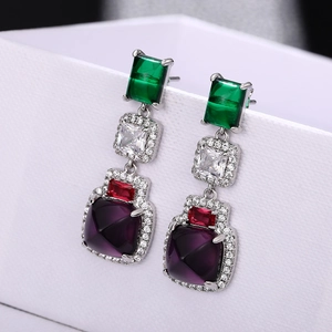 Dettaglio di orecchini a goccia color argento con smeraldo e gemme viola a più livelli