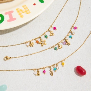 Detail of three gold-plated floral bracelets with colorful beads and cute animal charms