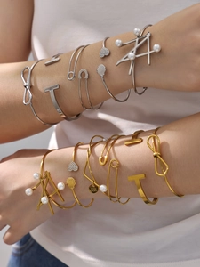 Detail shot of stacked 18k gold and silver geometric bangles with pearls and charms