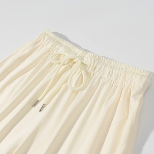Dettaglio dell'elastico in vita e coulisse bianca regolabile con punte in metallo sui pantaloni